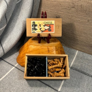 Puede incluir: Un juego de ajedrez de madera con piezas negras y marrones en una caja dividida. La caja tiene una etiqueta que dice "Chess".