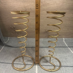 Peut inclure: Deux bougeoirs en m&eacute;tal dor&eacute; avec un design en spirale. Chaque bougeoir mesure environ 18 cm de haut.