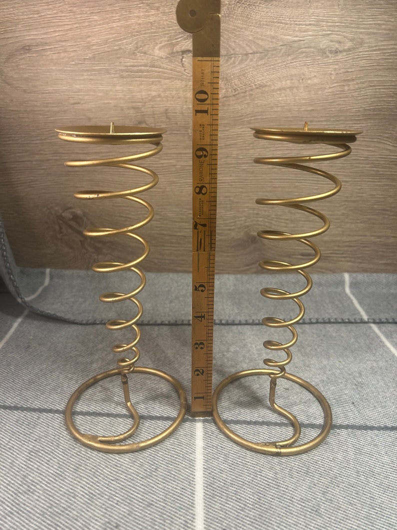 Peut inclure: Deux bougeoirs en m&eacute;tal dor&eacute; avec un design en spirale. Chaque bougeoir mesure environ 18 cm de haut.