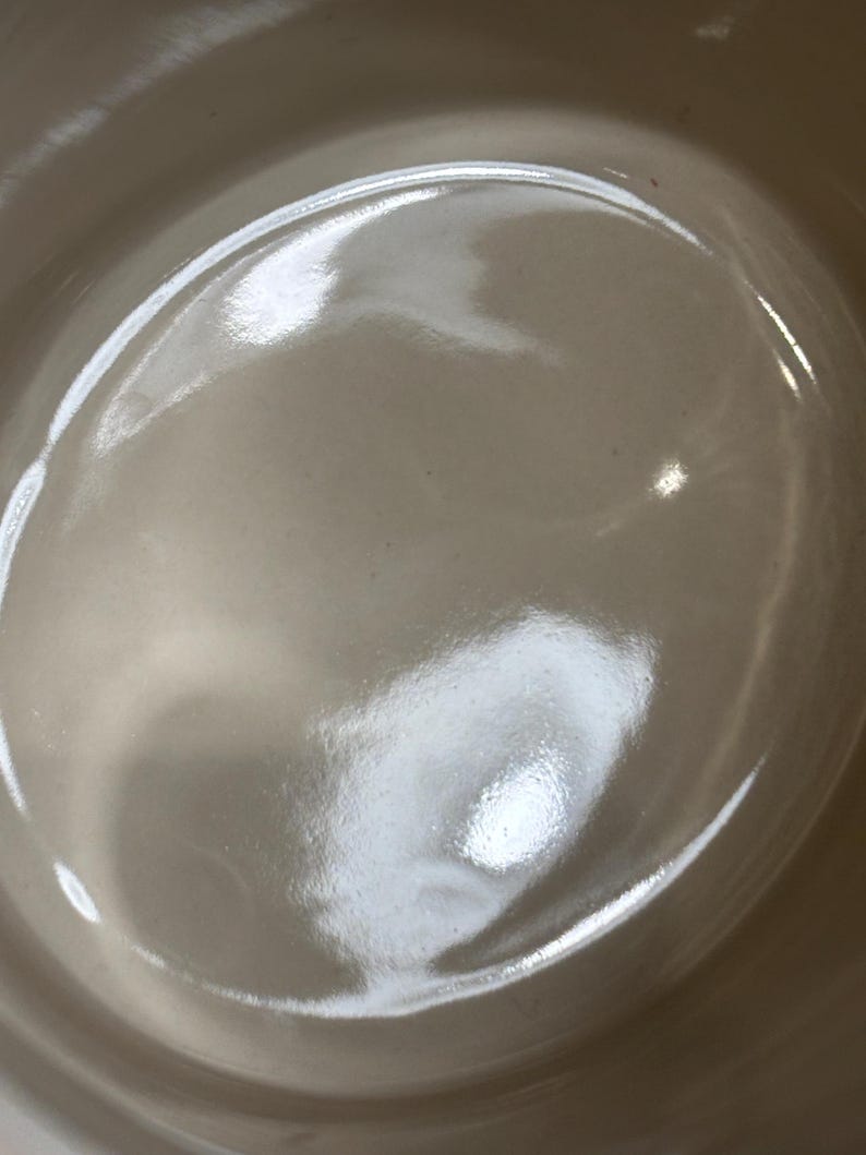 May include: A white ceramic bowl with a smooth, glossy finish. The bowl is empty and has a slight curve to the bottom.