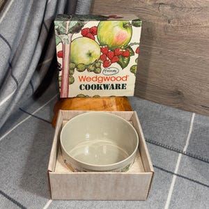 Puede incluir: Un bol Wedgwood Cookware con un diseño floral. El bol está en su caja original, que presenta una ilustración colorida de frutas y flores. La caja está etiquetada con "Wedgwood Cookware" y "Thomas".
