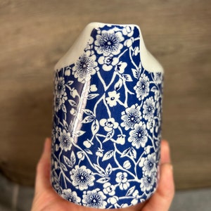 May include: A white ceramic milk jug with a blue and white floral pattern. The jug has a spout and a handle.