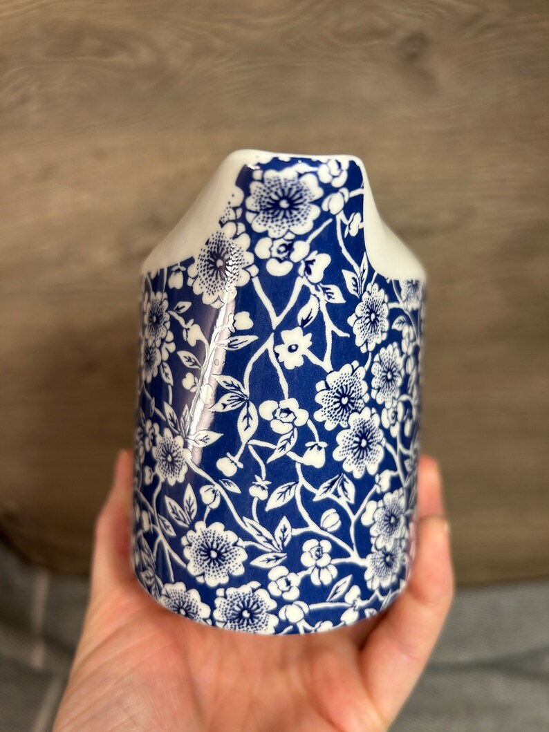 May include: A white ceramic milk jug with a blue and white floral pattern. The jug has a spout and a handle.