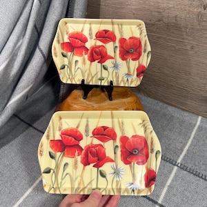 May include: Two rectangular trays featuring a floral design. The trays have a light yellow background with red poppies, wheat stalks, and white daisies. The trays are made of a glossy material.