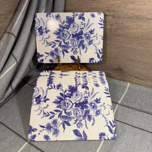 Puede incluir: Juego de manteles individuales con estampado floral azul y blanco. Los manteles individuales están hechos de un material duradero y presentan un diseño floral clásico.