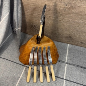 May include: Set of six silver butter knives with ivory handles. The knives are displayed on a wooden stand.