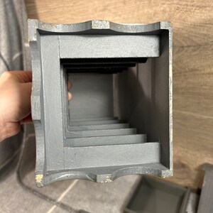 May include: A grey wooden box with a series of compartments. The box is open and the compartments are visible. The box is made of wood and has a rustic look.