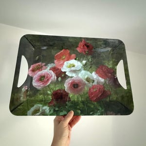 以下が含まれることがあります： 赤、ピンク、白のポピーの花柄が特徴の長方形のサービングトレイ。トレイは濃い緑色の背景と一体型のハンドルが付いています。花の配置は写実的なスタイルで描かれています。