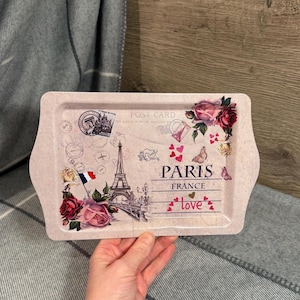 May include: A rectangular serving tray with a light pink background featuring a postcard design. The design includes the Eiffel Tower, roses, butterflies, and the words "Paris France" and "love".