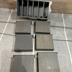 May include: Six small wooden boxes with a dark brown stain and a light brown wood grain pattern. The boxes are arranged in two rows of three. The boxes are empty and have a slightly distressed look.