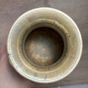 K&ouml;nnte beinhalten: Eine Messingvase mit einer breiten &Ouml;ffnung und einer glatten, polierten Oberfl&auml;che. Die Vase ist leer und scheint vintage zu sein.