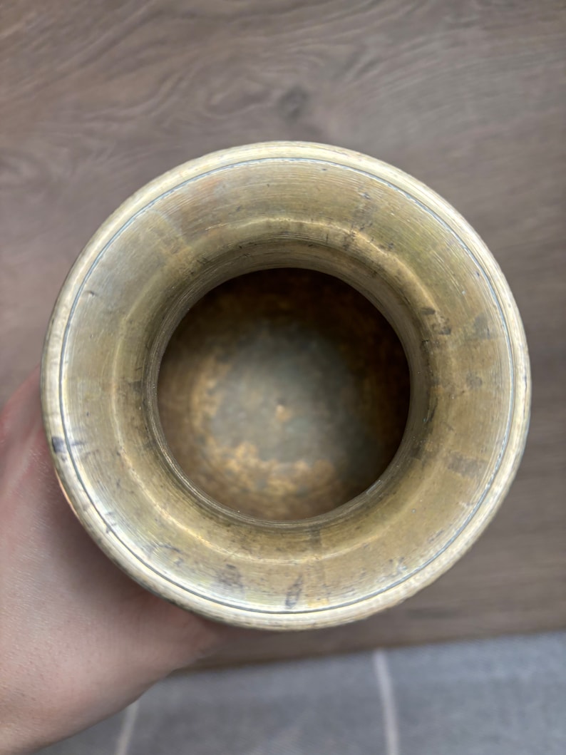 K&ouml;nnte beinhalten: Eine Messingvase mit einer breiten &Ouml;ffnung und einer glatten, polierten Oberfl&auml;che. Die Vase ist leer und scheint vintage zu sein.