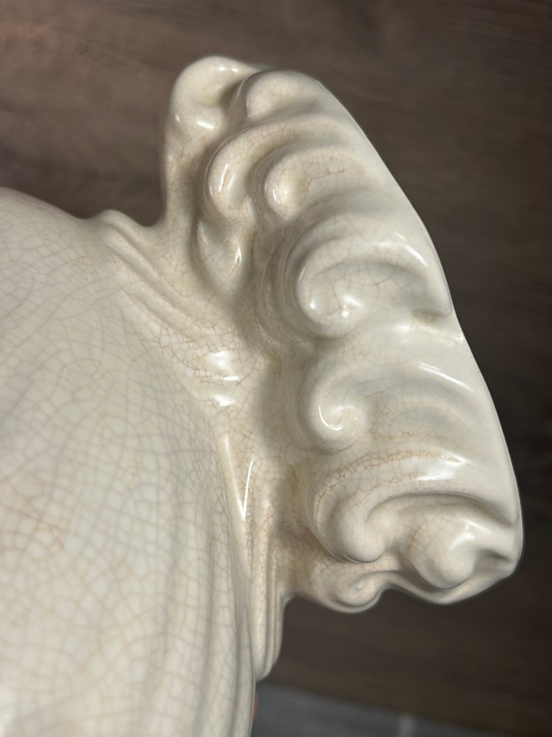 Op de afbeelding: Een wit keramisch beeld met een getextureerd oppervlak en een gedetailleerd, sierlijk ontwerp. Het beeld heeft een gladde, glanzende afwerking en een gekrakelde glazuur.