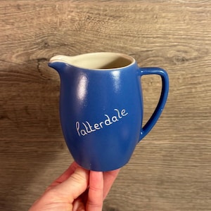 Może przedstawiać: Błękitny dzbanek ceramiczny z białą obwódką i uchwytem. Na boku dzbanka widnieje napis "Patterdale" w kolorze białym.