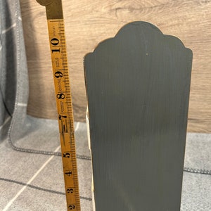 May include: A small wooden storage box with four drawers. The box is painted grey and white and has a decorative top. The box is about 15 cm tall.
