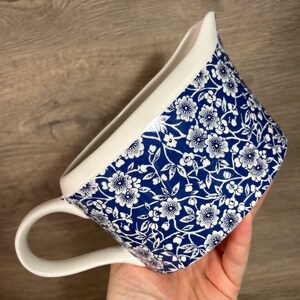 May include: A white ceramic jug with a blue and white floral pattern. The jug has a handle and a spout.