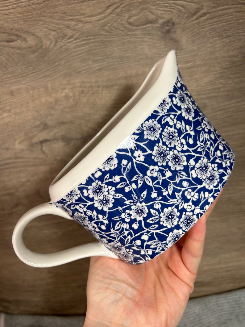 May include: A white ceramic jug with a blue and white floral pattern. The jug has a handle and a spout.