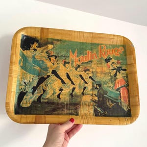 May include: Rectangular serving tray with a bamboo woven border. The tray features a vintage print of the Moulin Rouge with dancers and the text "Moulin Rouge" in orange. The print has a teal and orange color scheme.