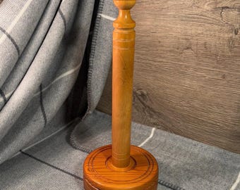 Peut inclure: Un porte-serviettes en papier en bois avec une base ronde et un bouton sur le dessus. Le porte-serviettes est en bois brun clair avec un motif de grain naturel.