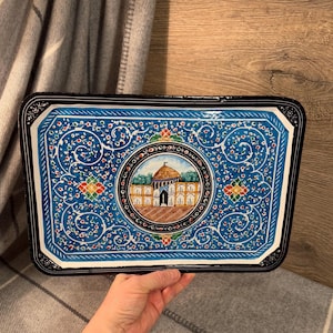 May include: A blue and black rectangular tray with a decorative design featuring a mosque with a gold dome. The tray is decorated with intricate floral patterns and colorful accents.
