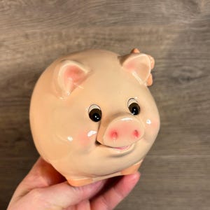 Alcancía vintage para bebé en color rosa pastel con forma de cerdito y cabeza de flor. Almacenamiento caprichoso para ahorrar dinero y monedas. Decoración para la habitación del bebé.