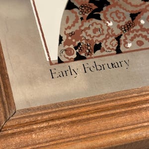 May include: A framed print with the text "Early February". The artwork features a design with brown, black, and white floral patterns. The frame is made of wood with a warm, reddish-brown finish.