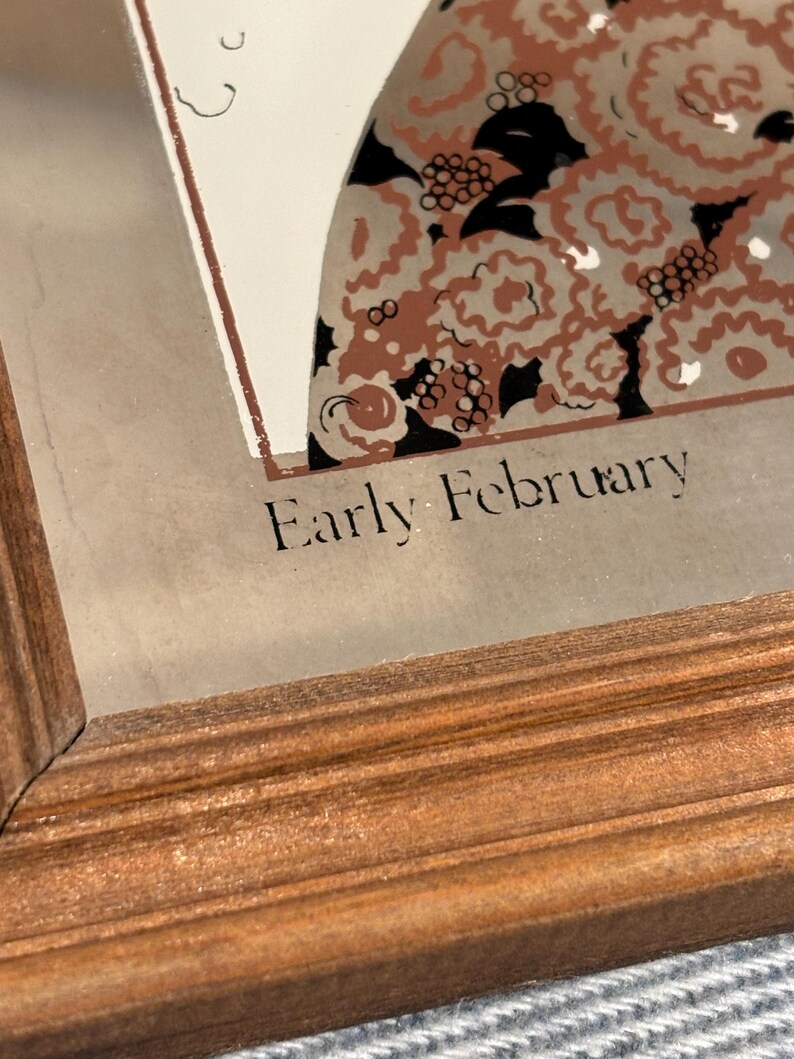 May include: A framed print with the text "Early February". The artwork features a design with brown, black, and white floral patterns. The frame is made of wood with a warm, reddish-brown finish.