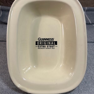 May include: Cream-colored, rectangular serving dish with rounded corners. The dish features the Guinness Original Extra Stout logo in black. The text reads "Brewer's Source 1821".