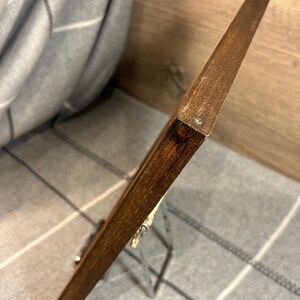 May include: A wooden picture frame with a dark brown finish. The frame is supported by a silver metal easel. The background is a gray and white plaid pattern.