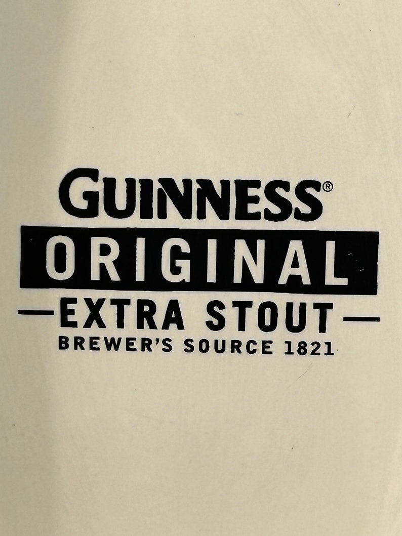 May include: Cream-colored background with the black text "Guinness Original Extra Stout Brewer's Source 1821". The Guinness logo is at the top, with "Original" in a black rectangle below it.