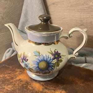 Op de afbeelding: Een set van drie keramische mokken met een gespikkelde, matte afwerking. De mokken zijn in crèmekleurige, lichtgrijze en donkergrijze tinten. Elke mok heeft een eenvoudig, minimalistisch ontwerp, ideaal voor koffie of thee.