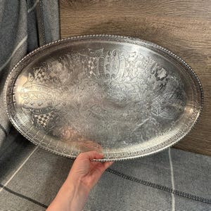 Può includere: Un vassoio da portata ovale in argento con un design in rilievo ornato. Il vassoio ha un bordo perlato.