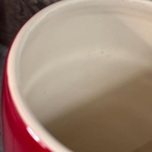 May include: A red ceramic canister with a white interior. The canister is empty and has a smooth, glossy finish.