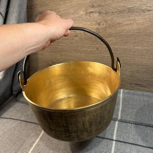 Può includere: Una grande pentola di rame antico con un manico in ferro nero. La pentola ha una patina usurata e invecchiata ed è perfetta per un arredamento rustico.