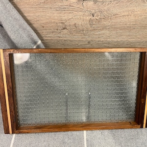 May include: A rectangular wooden tray with a glass insert. The tray has a dark brown wood frame with a light brown wood inlay. The glass insert has a textured pattern.
