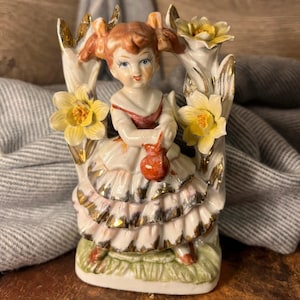 Vintage Ceramic Collectible Happy Girl Figurine with Blue Eyes, Pigtails and Holding a Bag in a Flower Doorway