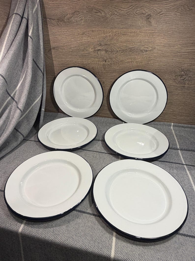 Pode incluir: Um conjunto de seis pratos redondos de esmalte branco, cada um com uma superf&iacute;cie lisa e uma borda fina azul-escura. Os pratos est&atilde;o dispostos em duas filas de tr&ecirc;s, exibindo um design limpo e uniforme com um acabamento brilhante.