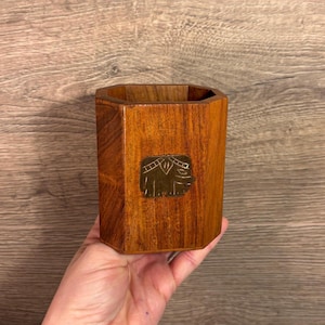 May include: A wooden octagonal pencil holder with a brass elephant design.