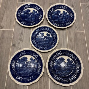 May include: Set of five blue and white porcelain dinner plates with a scalloped edge and a floral design. The plates feature a blue and white landscape scene with a bridge and trees.