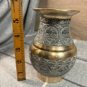 K&ouml;nnte beinhalten: Eine kleine, verzierte Messingvase mit einem komplizierten gravierten Design. Die Vase ist etwa 13 cm hoch und hat eine goldfarbene Oberfl&auml;che.