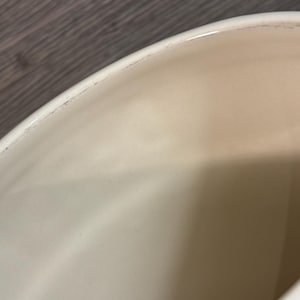 May include: Close-up of the inside of a red ceramic pot. The interior is white and smooth.