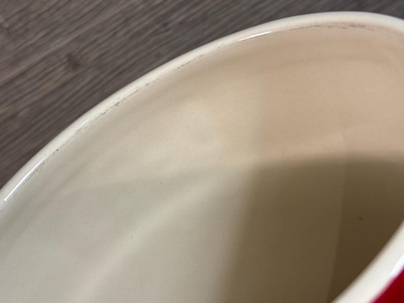 May include: Close-up of the inside of a red ceramic pot. The interior is white and smooth.