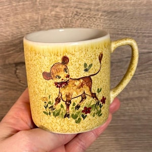 Vintage handgeschilderde New Devon Pottery Newton Abbot gemaakt in Engeland kleine beige gespikkelde mok met een Happy Baby koe kalf motief | Kitchenalia