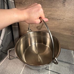 May include: A stainless steel pot with a handle. The pot is empty and has a shiny finish.