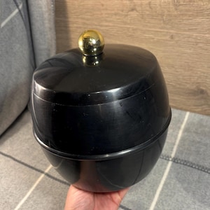 May include: Black ice bucket with a gold lid and knob. The bucket has a smooth, shiny finish.