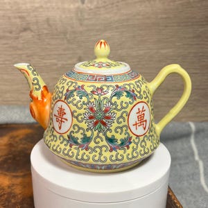 Könnte beinhalten: Ein Set aus drei Keramikbechern mit gesprenkelter, matter Oberfläche. Die Becher sind in Creme-, Hellgrau- und Dunkelgrautönen gehalten. Jeder Becher hat ein schlichtes, modernes Design und einen abgerundeten Griff.