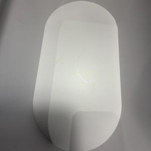 May include: A solid white, oval-shaped tray with a smooth, matte finish and rounded edges. The tray features a flat, elongated surface with a slightly raised rim, providing a clean and simple design for holding small items on a flat surface.