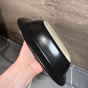 May include: A black, oblong-shaped serving dish with a white interior. The dish has a glossy finish and a slightly curved design. The text "STONE & SULLIVAN" is visible on the interior.