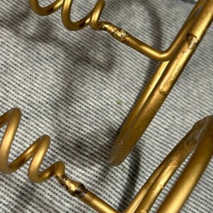 Peut inclure: Un porte-revues en fil m&eacute;tallique dor&eacute; avec un design en spirale. Le porte-revues est compos&eacute; de deux fils m&eacute;talliques qui sont pli&eacute;s en forme circulaire puis assembl&eacute;s. Le fil est lisse et brillant.