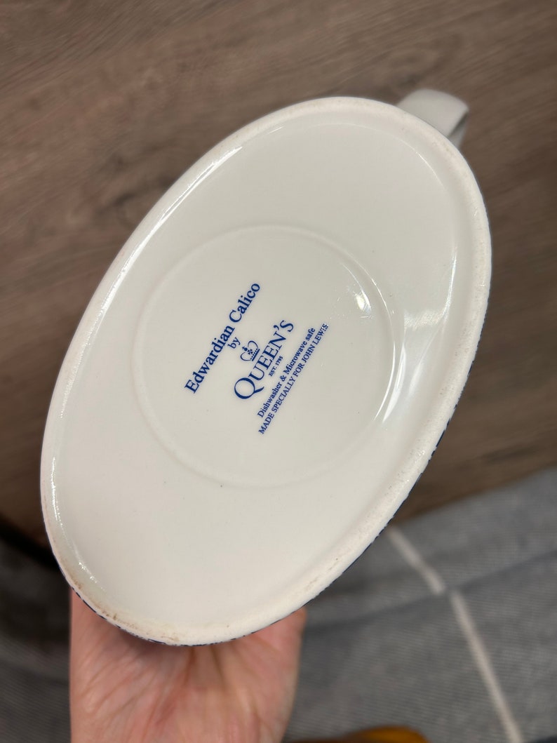 May include: White ceramic jug with a blue and white floral pattern. The base of the jug reads "Edwardian Calico by Queen's Dishwasher & Microwave Safe Made Specially For John Lewis".
